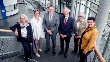 Die genannten Personen stehen auf der Treppe des Hörsaalgebäudes A14 und blicken nach oben Richtung Fotograf.